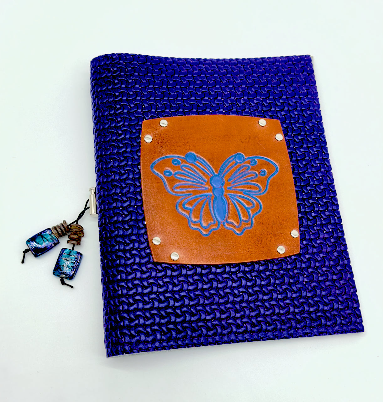 wide shot of blue leather journal cover featuring an embossed butterfly image on brown leather that is inked with blue